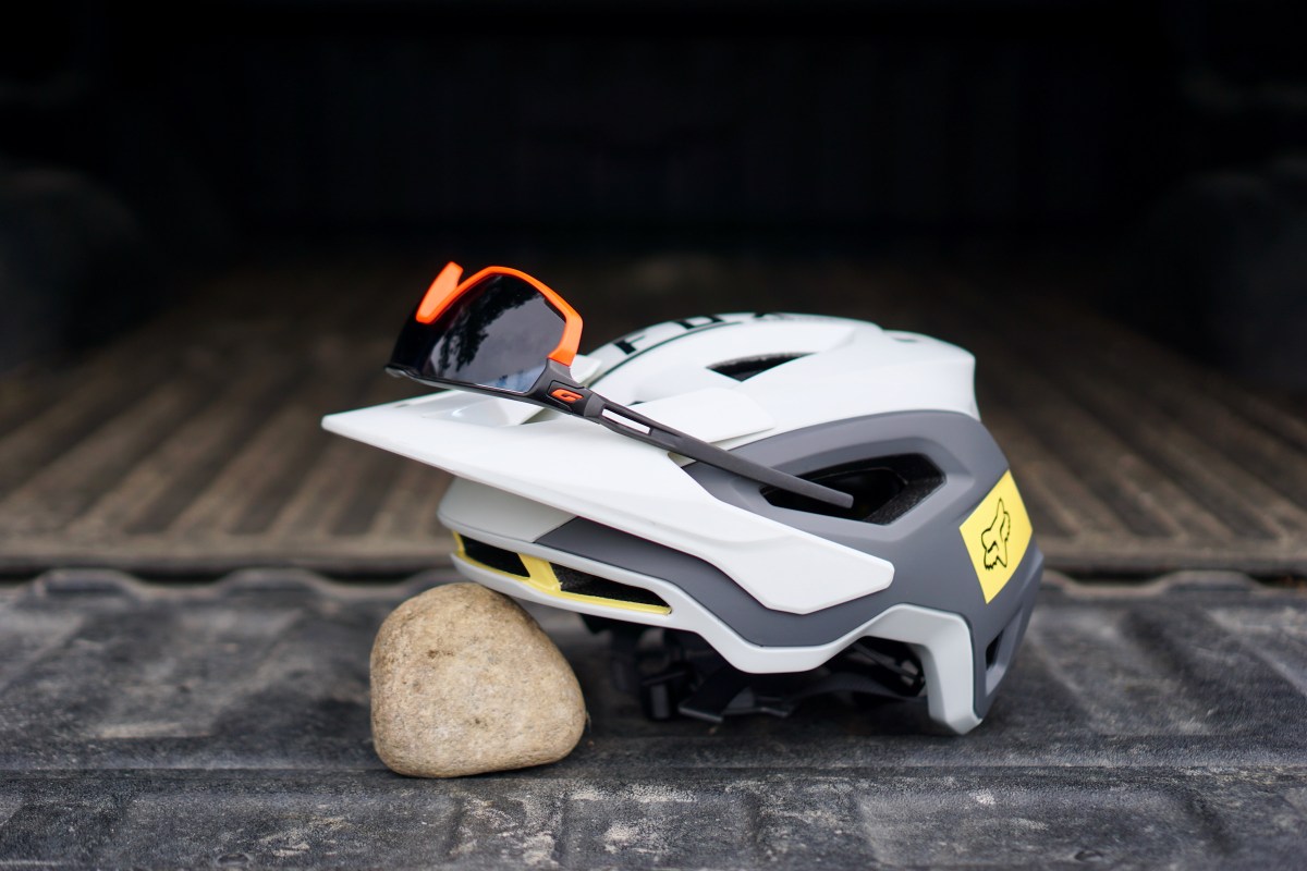 Julbo Rush sunglasses sitting on gray Fox Speedframe Pro mountain bike helmet.