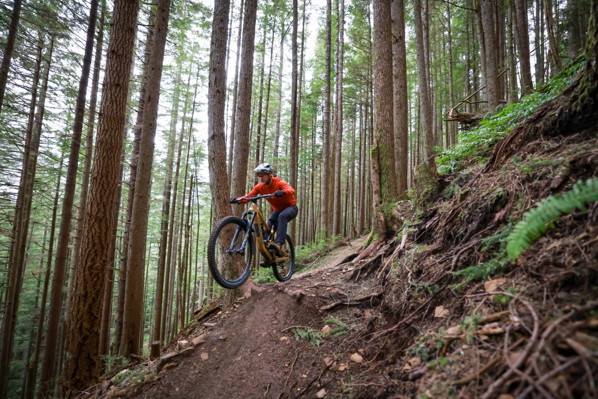 Mountain biker jumping over root and catching in the Fox Speedframe Pro mountain bike helmet.