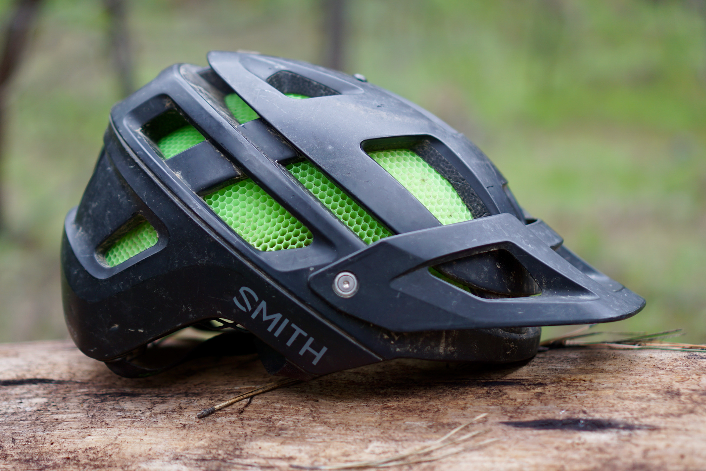 Black and green Smith Forefront 2 mountain bike helmet sitting on a log.