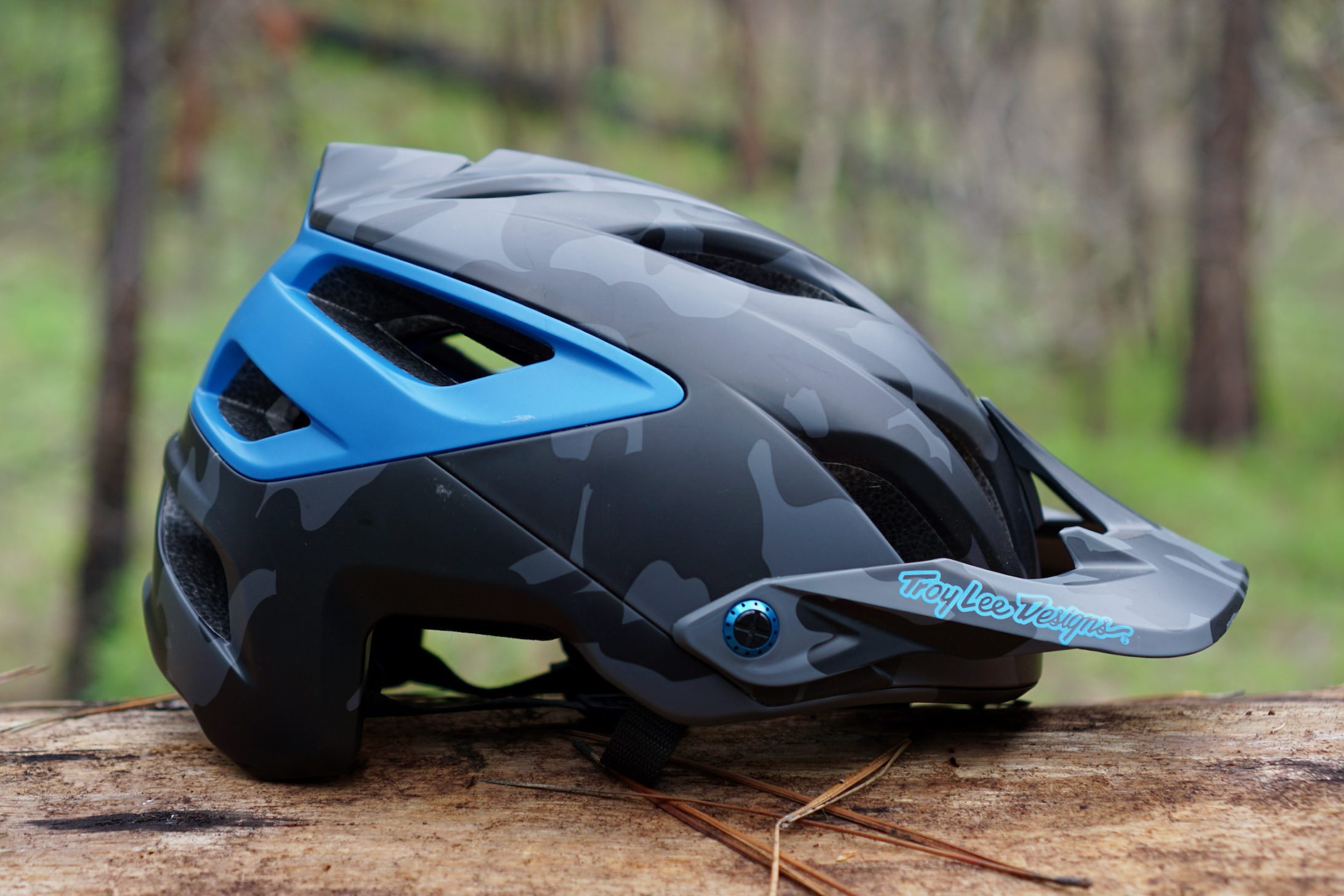 Black and blue Troy Lee Designs A3 mountain bike helmet sitting on a log.
