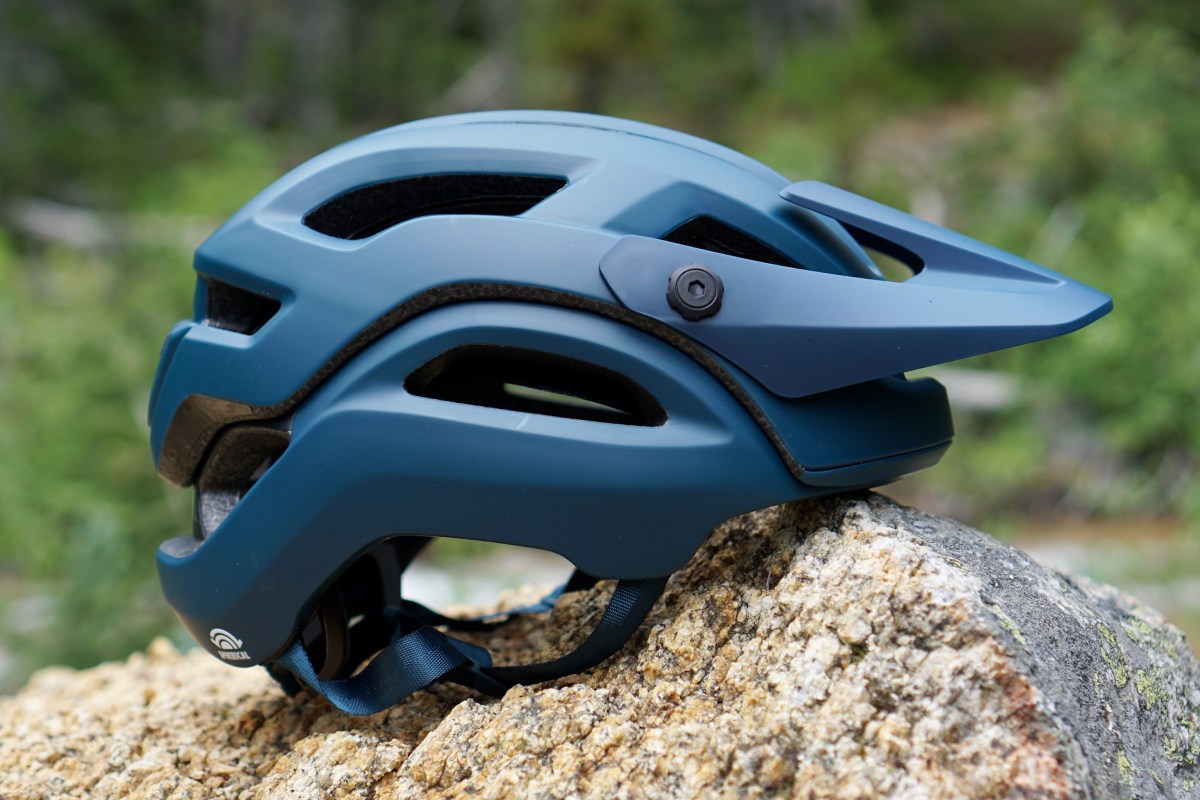 Dark blue Giro Manifest Spherical mountain bike helmet sitting on a rock (profile view).