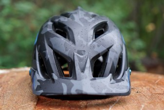Black Troy Lee Designs A3 mountain bike helmet sitting on a stump (front view).