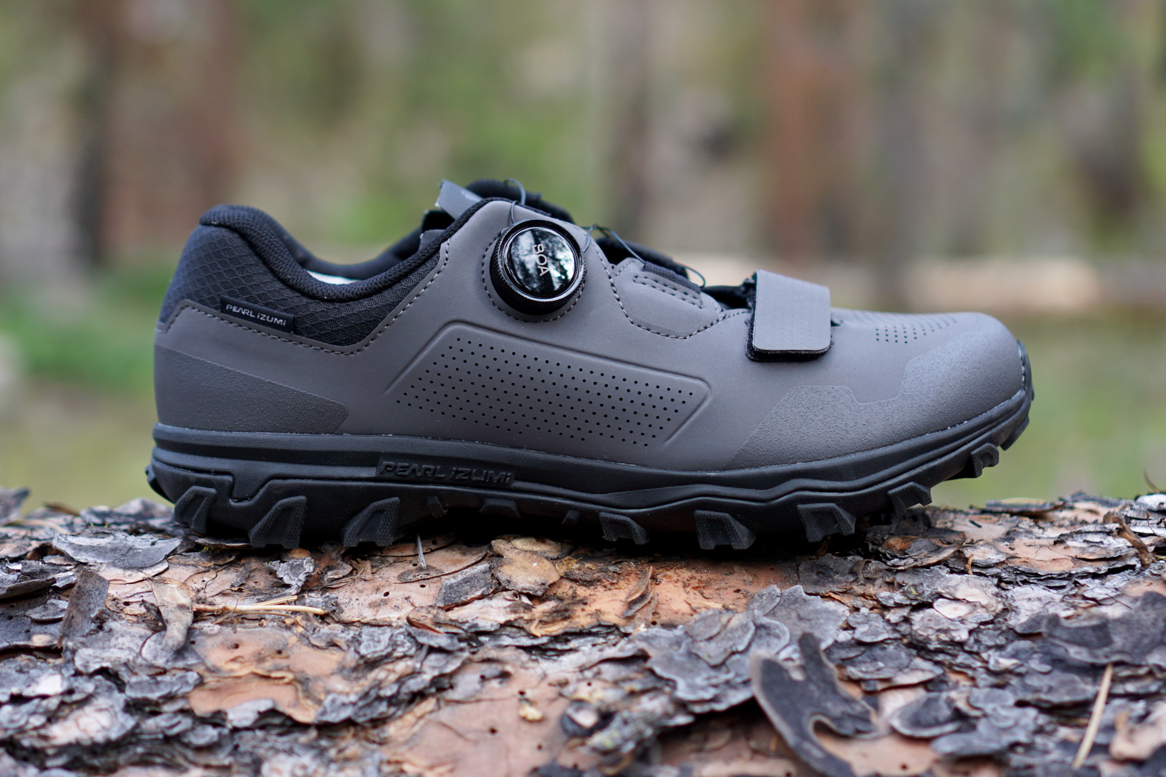 Grey Pearl Izumi X-Alp Summit clipless mountain bike shoe profile sitting on log in the woods.