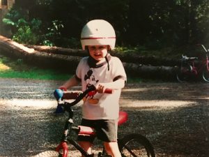 Old photo of Erik Nilson as a kid riding a bike and wearing a big white foam helmet on a red huffy bike.
